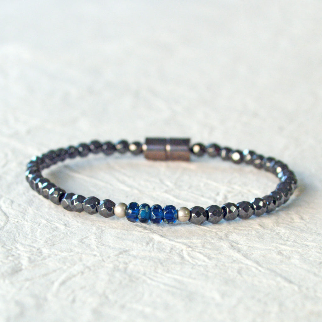 Magnetic hematite bracelet handcrafted with black faceted magnetic hematite beads. In the center are 4 blue czech glass beads surrounded by brushed antique silver spacer beads. Bracelet is secured with a strong magnetic clasp.