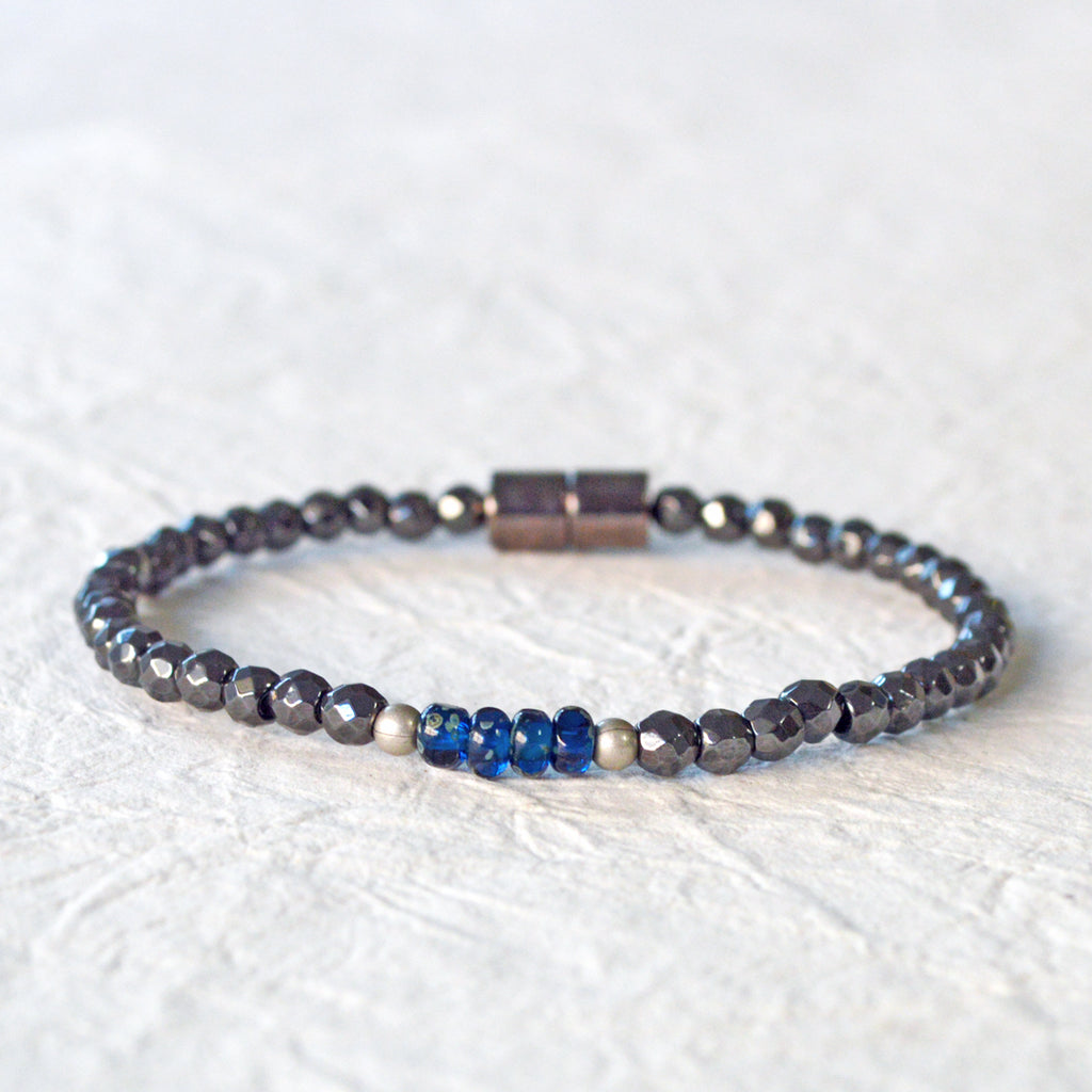 Magnetic hematite bracelet handcrafted with black faceted magnetic hematite beads. In the center are 4 blue czech glass beads surrounded by brushed antique silver spacer beads. Bracelet is secured with a strong magnetic clasp.