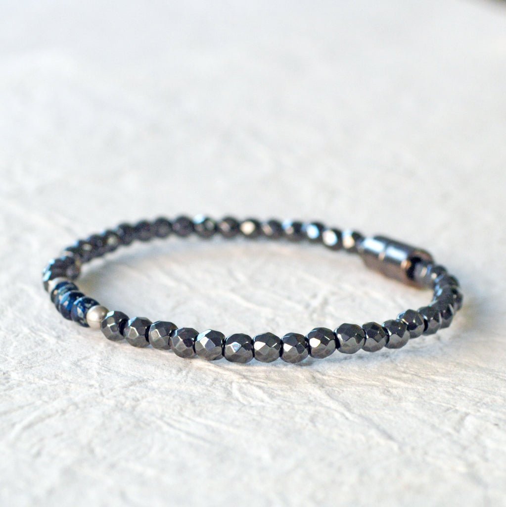 Magnetic hematite bracelet handcrafted with black faceted magnetic hematite beads. In the center are 4 blue czech glass beads surrounded by brushed antique silver spacer beads. Bracelet is secured with a strong magnetic clasp.