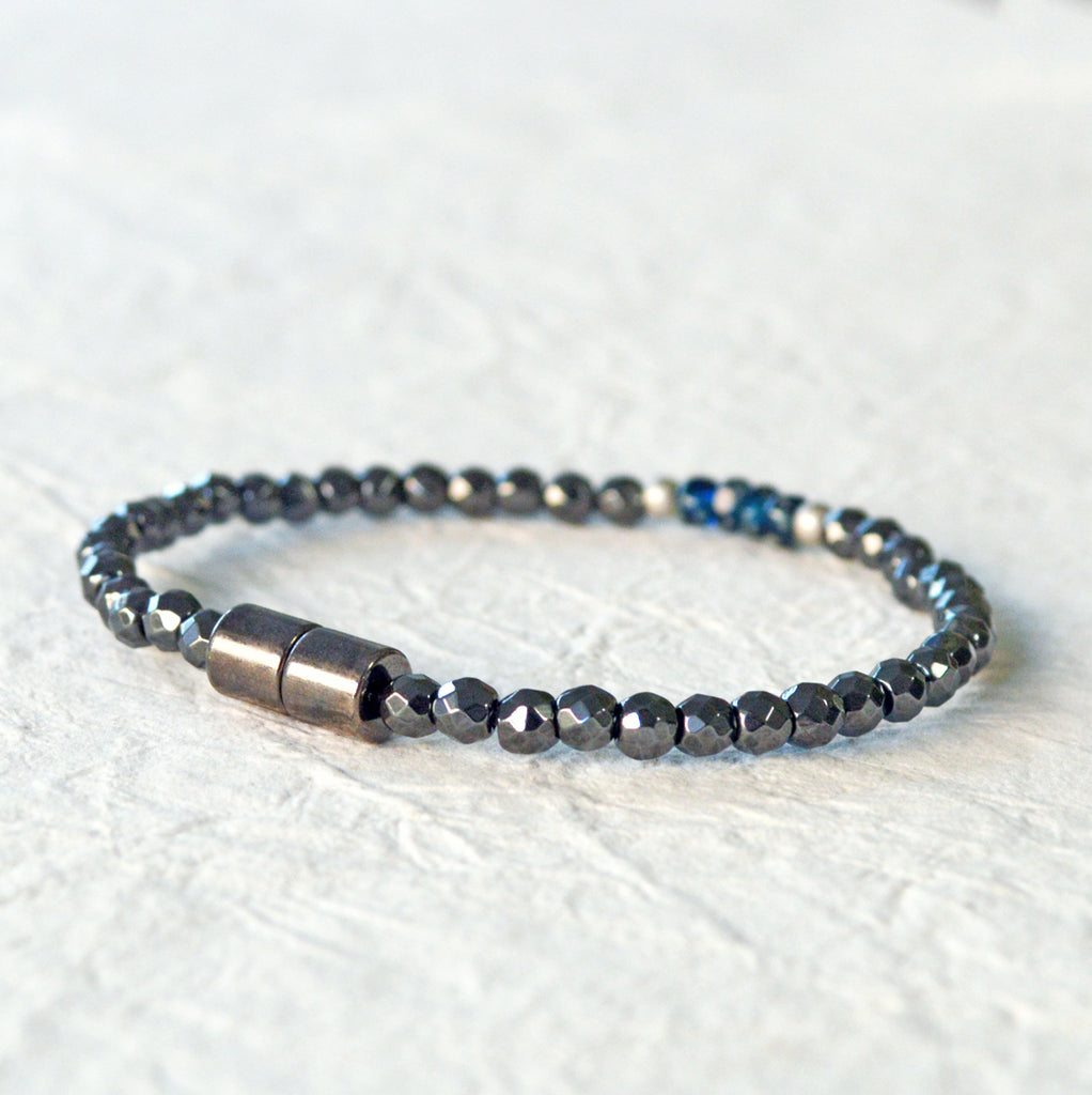 Magnetic hematite bracelet handcrafted with black faceted magnetic hematite beads. In the center are 4 blue czech glass beads surrounded by brushed antique silver spacer beads. Bracelet is secured with a strong magnetic clasp.