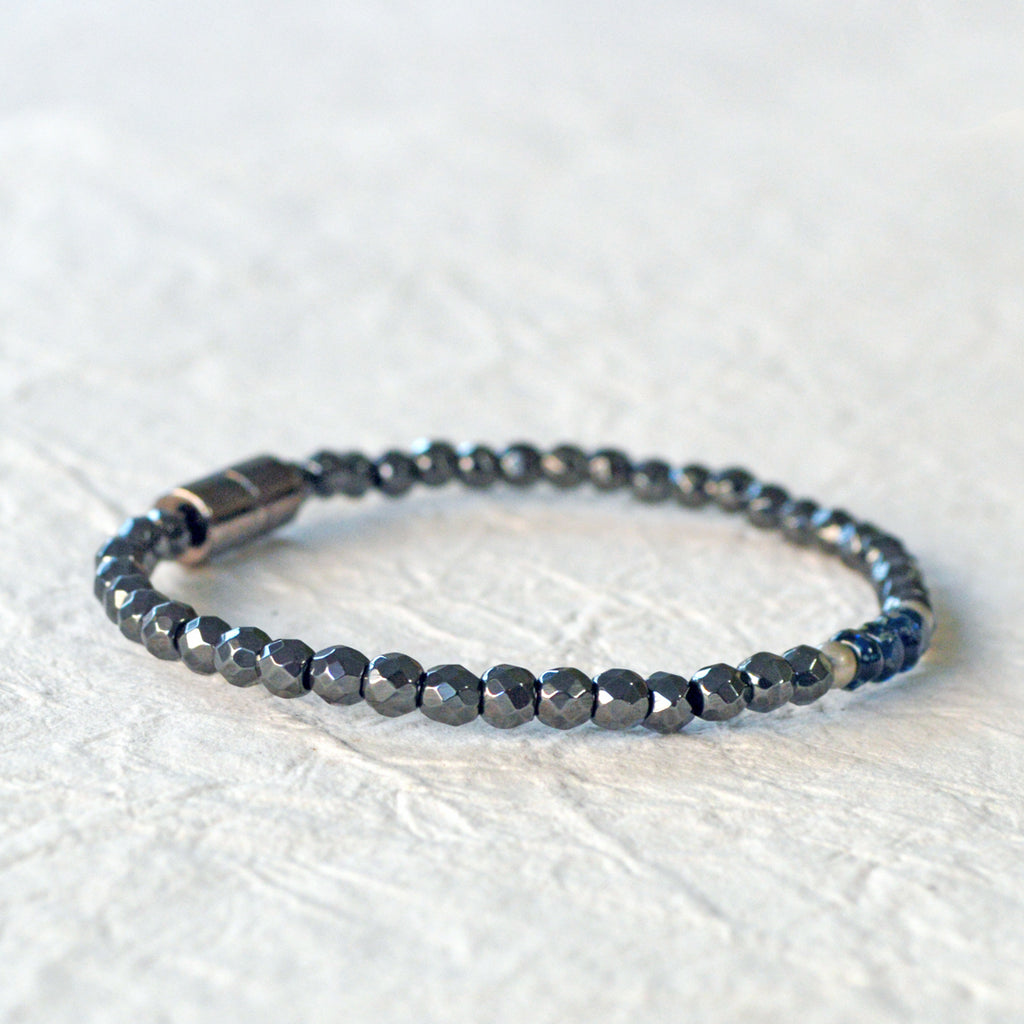Magnetic hematite bracelet handcrafted with black faceted magnetic hematite beads. In the center are 4 blue czech glass beads surrounded by brushed antique silver spacer beads. Bracelet is secured with a strong magnetic clasp.