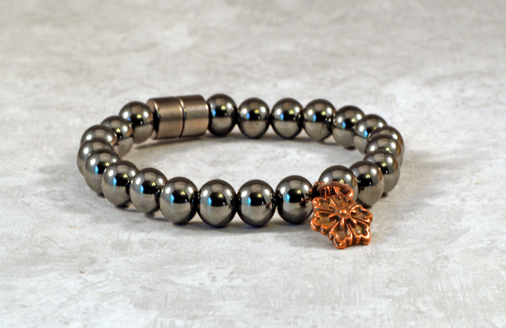 Magnetic therapy bracelet crafted with high power magnetic hematite beads with an antique flower charm in the center. Secured with a strong and easy-to-use magnetic clasp.