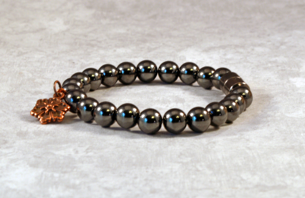 Magnetic therapy bracelet crafted with high power magnetic hematite beads with an antique flower charm in the center. Secured with a strong and easy-to-use magnetic clasp.
