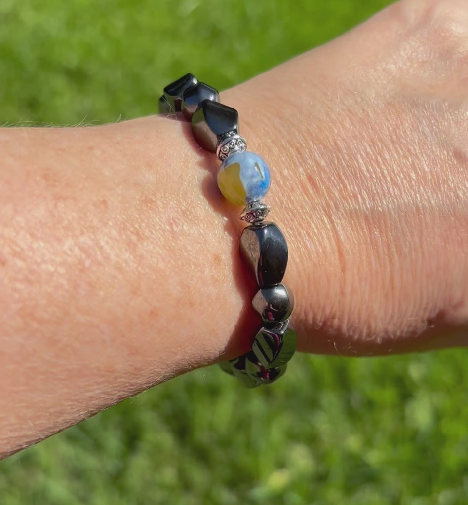 Magnetic bracelet for women handcrafted with powerful black magnetic hematite beads with a lovely blue and yellow fire agate gemstone bead in the center. Bracelet is secured with a strong magnetic clasp.