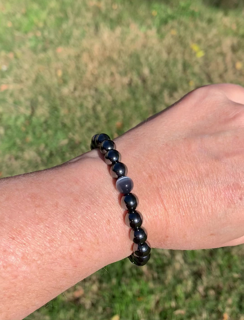 Black Hematite Magnetic bracelet handcrafted with powerful hematite magnetic beads with a grey cat's eye bead in the center. Secured with a strong and easy-to-use magnetic clasp.
