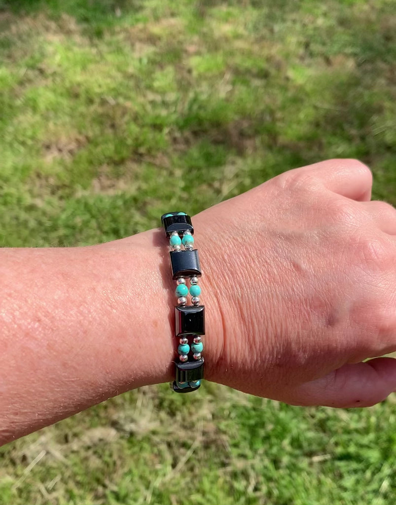 Two strand magnetic energy bracelet handcrafted with black magnetic hematite beads paired with turquoise magnesite beads and stainless steel silver beads. It is secured with a strong and easy-to-use magnetic clasp.